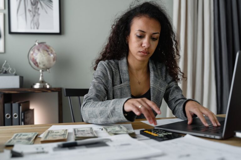 A Woman in Plaid Blazer Using Her Laptop and Mobile Phone for Passive Income